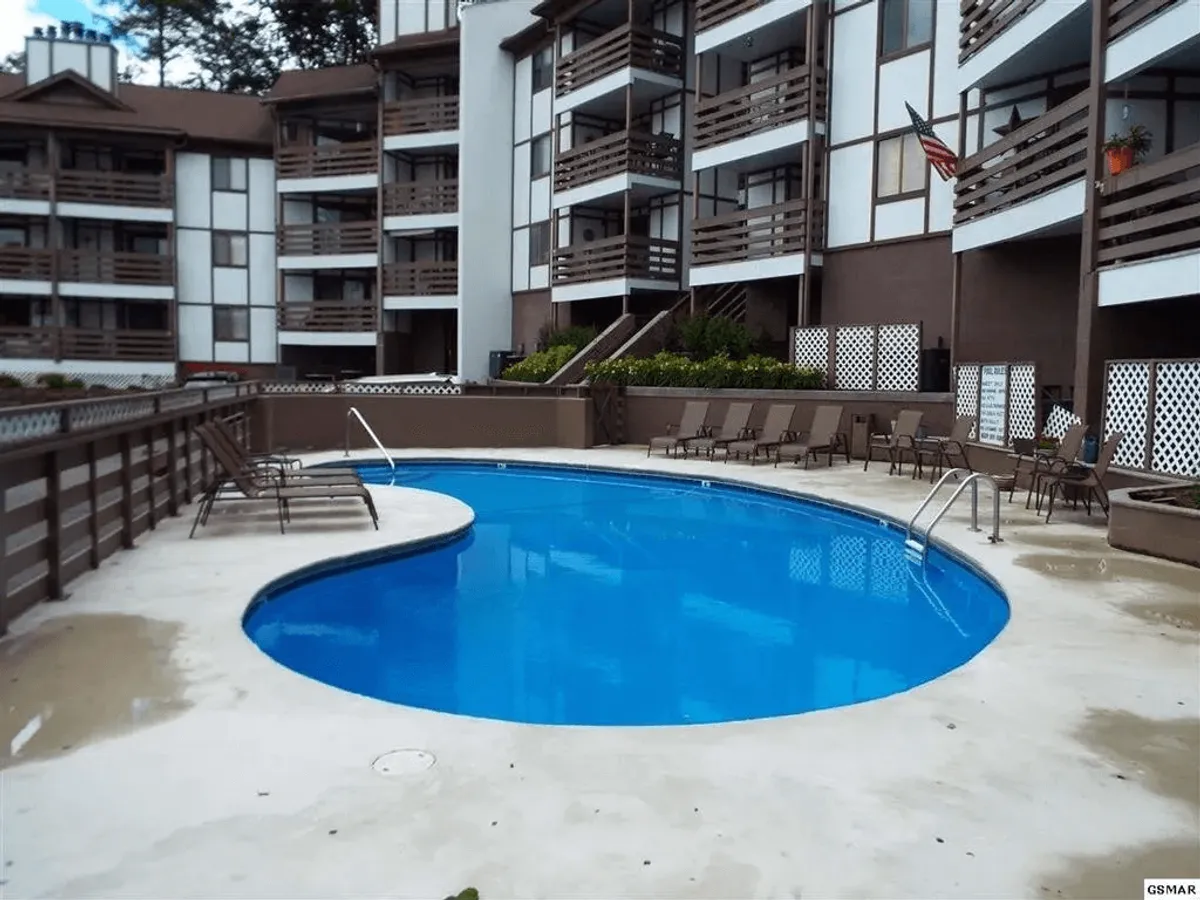 This exterior shot captures the swimming pool with surrounding seating areas and the architecture of the condo building in the background. The inviting atmosphere suggests opportunities for both social gatherings and quiet moments, highlighting the shared nature of the amenity.