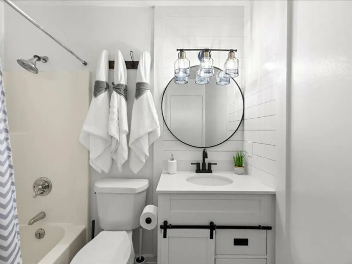 A fresh and inviting bathroom with a round mirror, elegant hanging light fixtures, a modern sink with a faucet, and plush towels on a rack. The design is clean and contemporary, creating an atmosphere of renewal and relaxation.