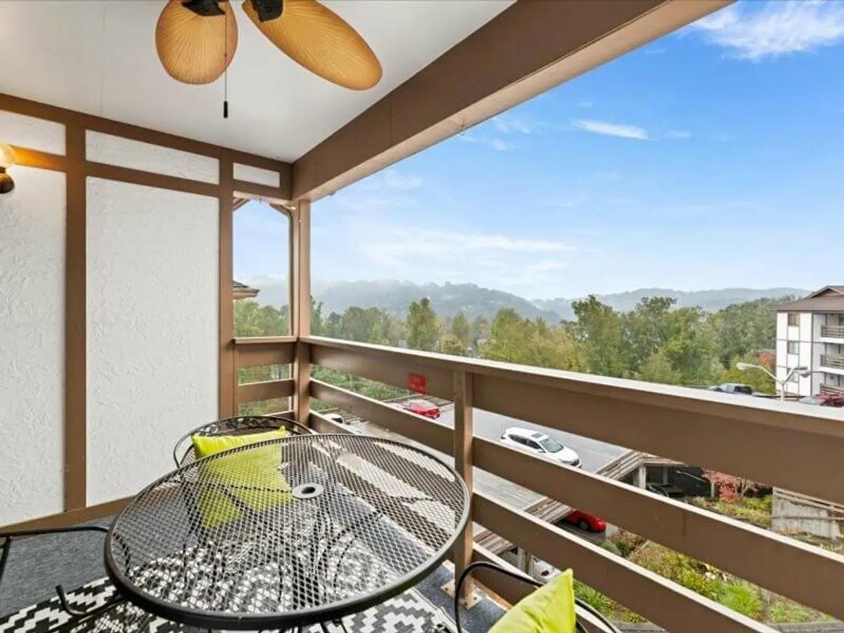 An inviting outdoor seating area overlooks the surrounding landscape, featuring comfortable seating under a decorative ceiling fan. The view is serene, perfect for relaxing after a day of adventure.
